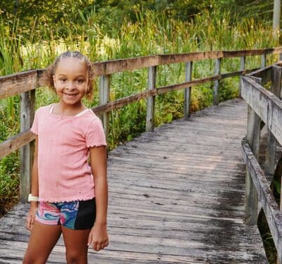 girl standing on bridge in wetlands