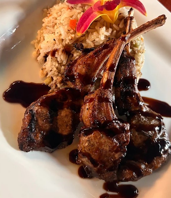 lamb chops on a plate with rice and a flower